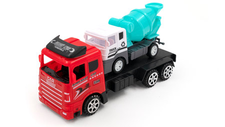 Toy truck with trailer transports cement mixer on white background.の写真素材
