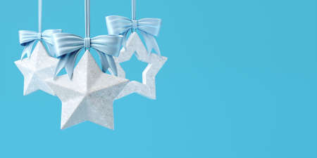 Christmas tree toys in the form of silver stars with light blue bows. 3d illustration is in gentle blue colors, horizontal format with space for text.の写真素材