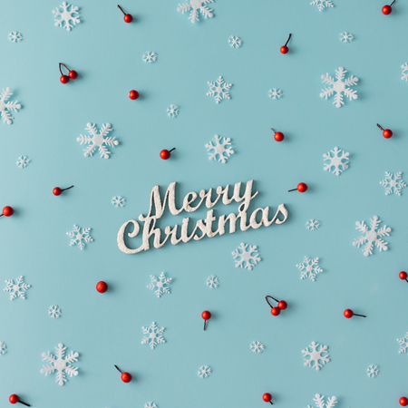 Christmas pattern made of snowflakes and red berries on blue background. Winter concept. Flat lay.の写真素材