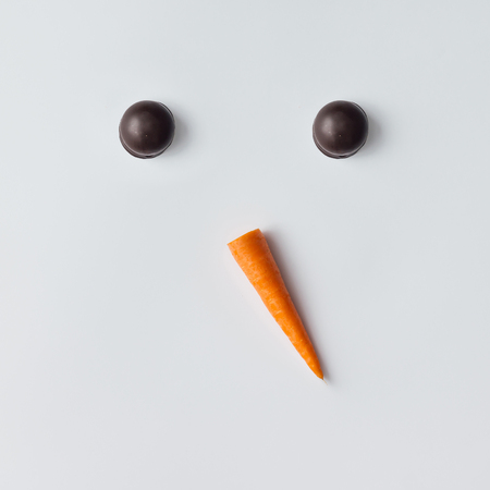 Snowman face made of cookies and carrot. Minimal holiday concept. Christmas flat lay.の写真素材