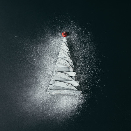 Minimal Christmas tree with sugar snow on dark background. Flat lay holiday concept.の写真素材