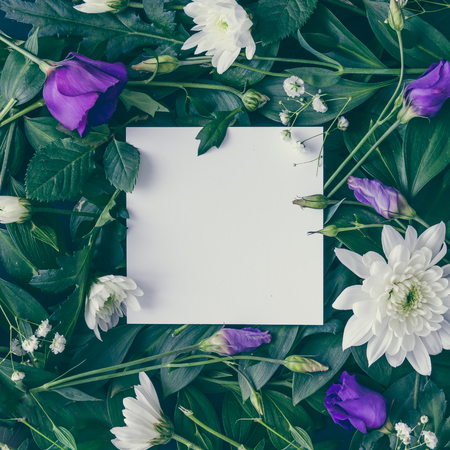 Creative layout made of flowers and leaves with paper card note. Flat lay. Nature conceptの写真素材