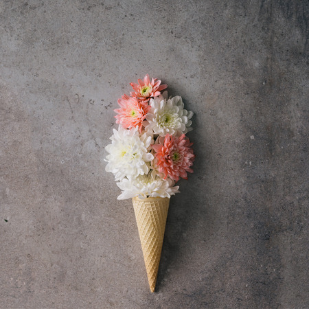 Pink and white flowers in ice cream cone on marble background. Minimal concept. Flat lay.の写真素材