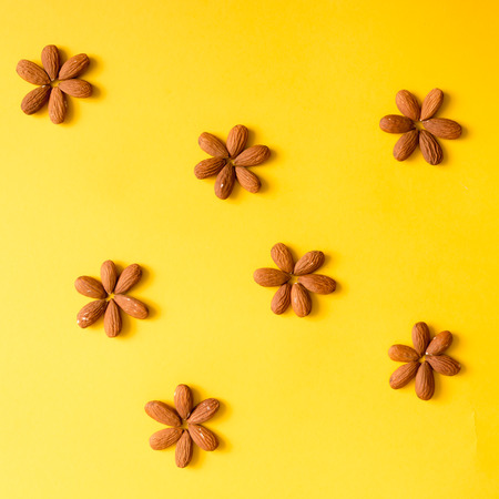Creative arrangement of nuts on yellow background. Flat lay.