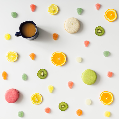 Colorful bright fruit pattern with coffee mug and sweets on white background. Flat lay.の写真素材