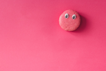 Macaroon with eyes on pink background. Flat layの写真素材
