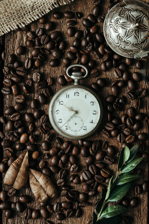 Creative arrangement of Coffee beans with watch on wooden background. Flat layの写真素材