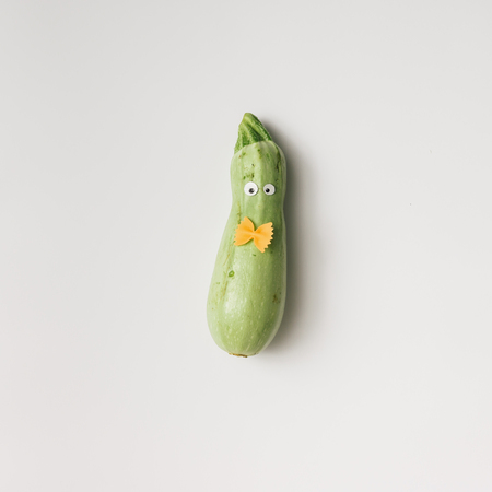 Zucchini with eyes and bowtie on white background. Minimal conceptの写真素材