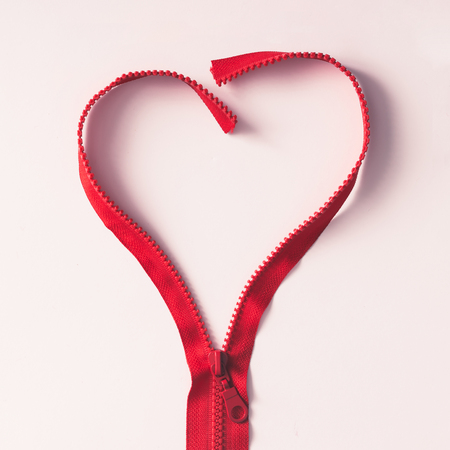 Red zipper in shape of a heart on white background. Flat layの写真素材