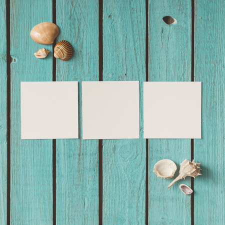 Three blank photos on wooden summer background with seashells. Flat lay.
