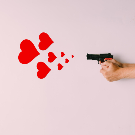 Pistol firing hearts on bright background. Love conceptの写真素材
