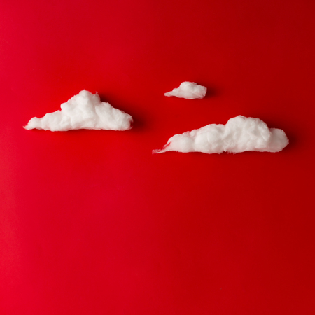 White fluffy clouds on red background. Love concept. Flat lay.
