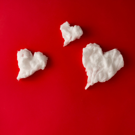 Heart shape white fluffy clouds on red background. Love concept. Flat lay.の写真素材