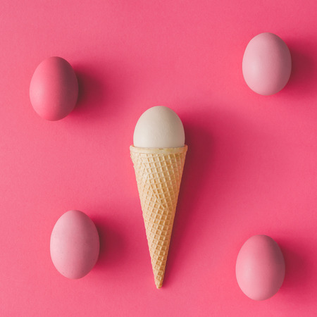 Ice cream cone with egg on pink background. Minimal Easter concept. Flat lay.の写真素材