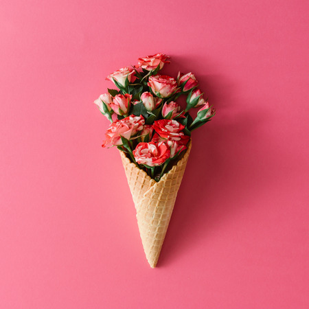 Ice cream cone with colorful flowers on pink background. Flat lay. Minimal summer concept.の写真素材