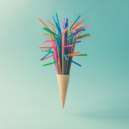 Ice cream cone with colorful drinking straws on bright blue background. Minimal food concept.の写真素材