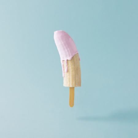 Banana with ice cream stick on pastel blue background. Food creative concept.