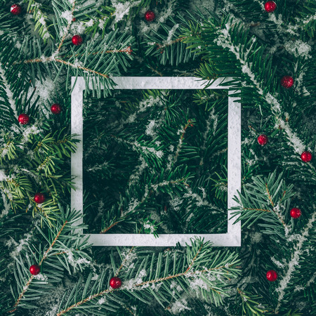 Creative layout made of Christmas tree branches with snow and paper card note. Flat lay. Nature New...