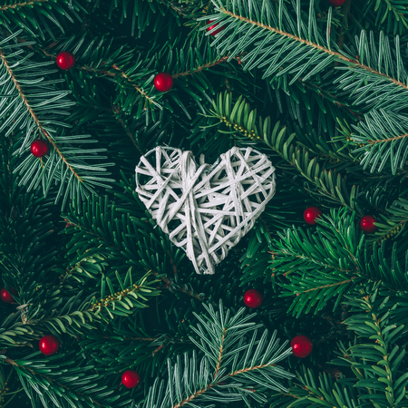 Creative layout made of Christmas tree branches with heart decoration. Flat lay. Nature New Year concept.の写真素材