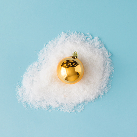 Egg made of golden Christmas bauble decoration and snow. Flat lay. Christmas concept.の写真素材