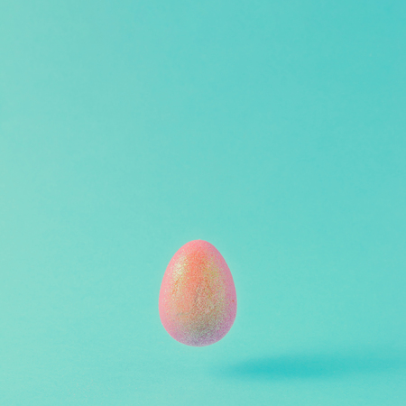 Holographic Easter egg on pastel blue background. Minimal Easter holiday concept.