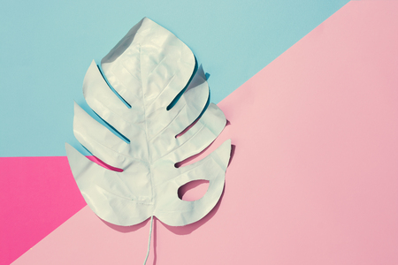 Creative layout made of painted tropical leaves on pastel pink and blue background. Minimal summer exotic concept with copy space.の写真素材