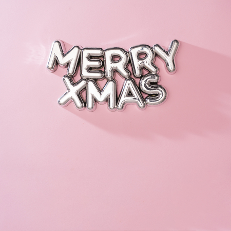 Shiny MERRY XMAS Christmas tree decoration with pink background. Minimal New Year party holiday concept. Flat lay.の写真素材