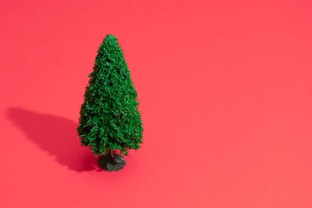 Minimal composition background of green Christmas tree on pastel red. New Year concept.の写真素材