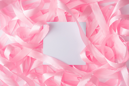 Pink satin ribbon background with paper card note. Flat lay. Minimal love concept.の写真素材
