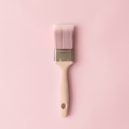 Creative concept made with paint brush and pastel pink background. Minimal flat lay.