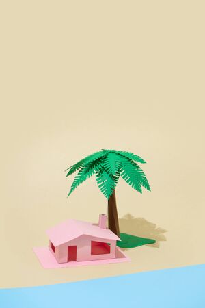 Paper holiday beach house with palm tree and sea. Vacation minimal conceptual background.の写真素材