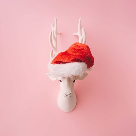 Christmas reindeer decoration with  Santas hat and pink background. Minimal creative concept.の写真素材