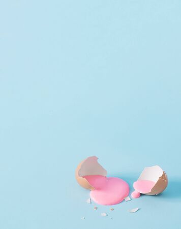 Eggshell with pastel pink paint. Creative copy space on blue background. Minimal Easter holiday...