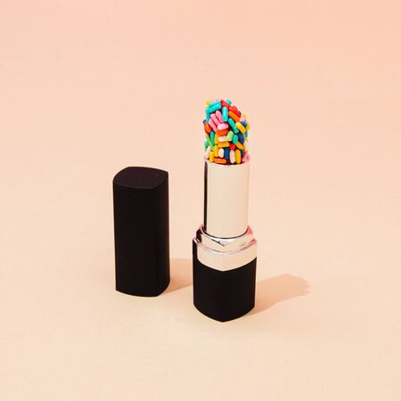 Creative concept with lipstick with colorful cake sprinkles. Minimal make up background.の写真素材