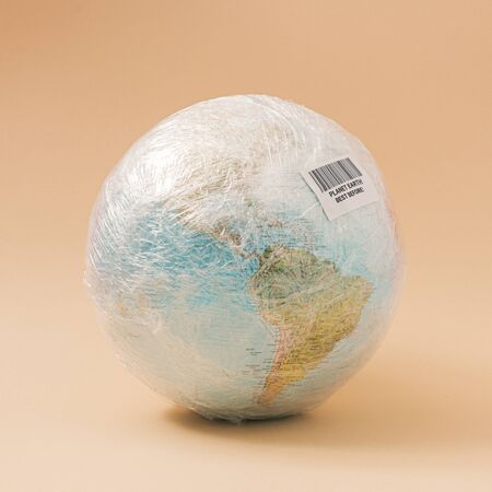 Planet Earth in stretch wrap plastic with best before sticker. Minimal enviromental concept.の写真素材