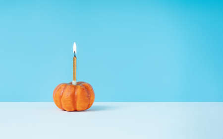 Halloween minimal concept with pumpkin and birthday candle. Creative holiday party backgroundの写真素材
