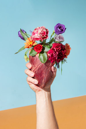Hand holding heart with blooming spring flowers. Minimal love concept. Nature creative idea.の写真素材