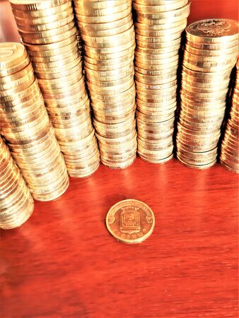 iron coins are stacked on top of each other in piles on the table and one coin lies nearbyの写真素材