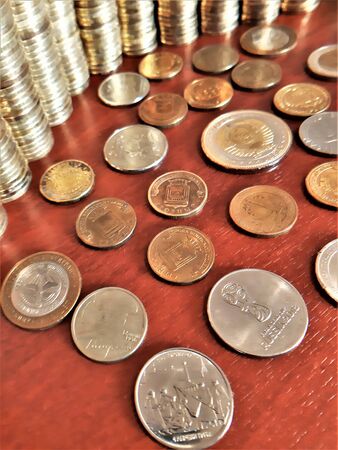 iron coins of different denominations and different colors are scattered on the tableの写真素材