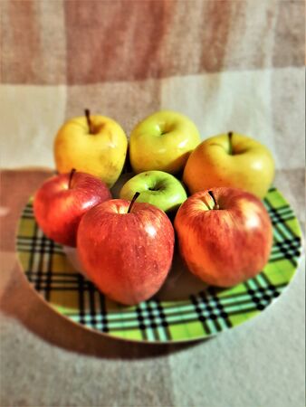 yellow red green apples in the amount of seven pieces lie on a plateの写真素材