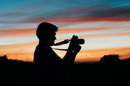A man taking pictures with his analog camera in a sunset at golden hourの写真素材