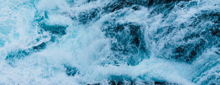 White sea foam produced when the waves collide with the rocks of the coastの写真素材