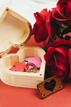 A heart-shaped box with hearts, a ring and red roses.