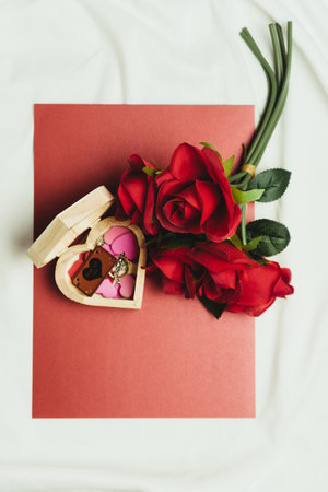 A heart-shaped box with hearts, a ring and red roses.の写真素材