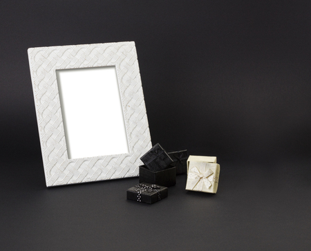 White photo-frame on a black background, with small gift-boxes in black and white. Black background.の写真素材