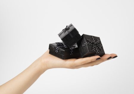 Female hand holding a three black gift-boxes on a palm. Isolated on white background. Shallow depth photo.の写真素材
