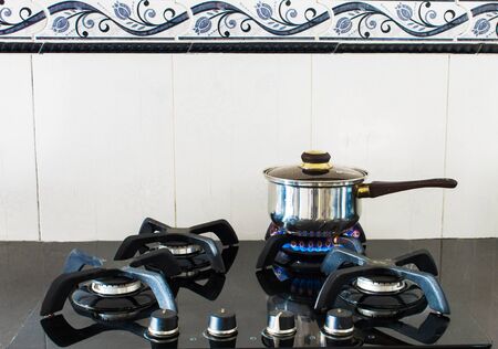 lighted stove with pot preparing food in kitchenの写真素材