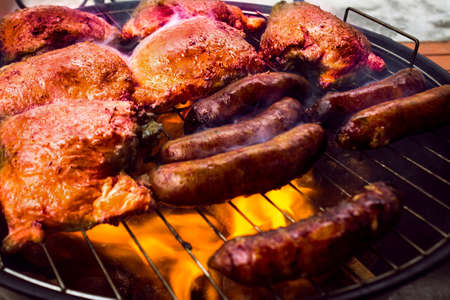 barbecue with chicken and sausages on charcoalの写真素材