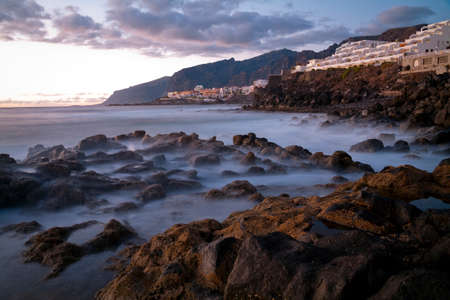 Los Gigantes Rocks in the evening with smoke effect on the waterの写真素材