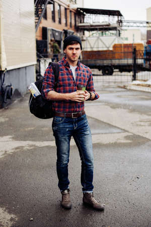 A man walking down the street in autumn in a shirt with a backpackの写真素材